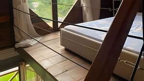 A bedroom with a bed, a window with curtains, and a view of the outdoors. - Sítio Solar di Stella (Itatiaia)
