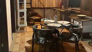 A dining area with a wooden table and chairs, a white cabinet, and a staircase. - Sítio Solar di Stella (Itatiaia)
