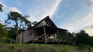 A single-story building with a sloped roof, a balcony, and a small window. - Sítio Solar di Stella (Itatiaia)
