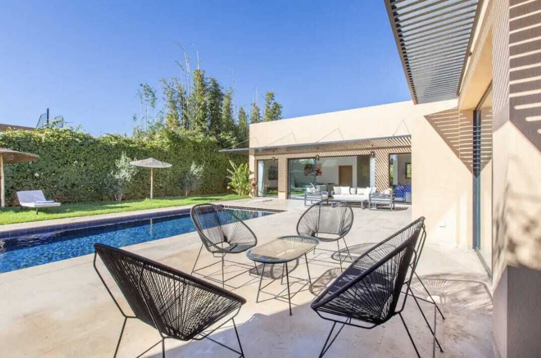 A modern outdoor pool area with lounge chairs and a glass-enclosed patio.