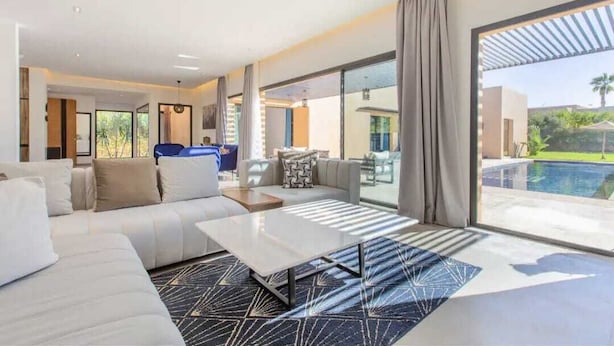 Een moderne woonkamer met een groot raam, een zwembad en uitzicht op de omgeving.