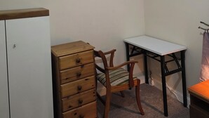 Habitació petita i ben il·luminada amb un taulell de fusta, una cadira, un escriptori i una làmpada al sostre.