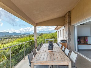 A wooden table with chairs on a balcony overlooking a mountainous landscape. - Villa Bella Vista Di Pinarello (Zonza)
