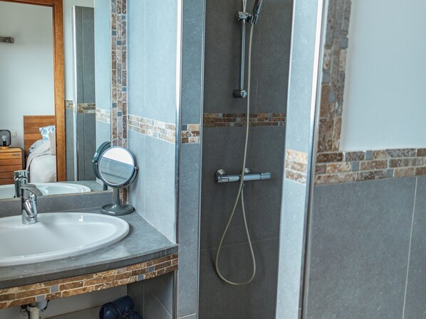 A bathroom with a sink, mirror, and shower.