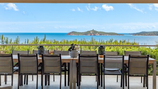 Un espacio de comedor al aire libre con vista al mar y una isla distante.