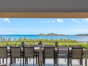 An outdoor dining area with a view of the sea and a distant island.