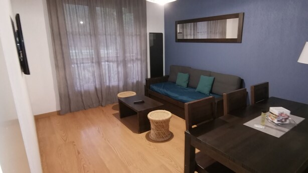 Ein kleiner, gut beleuchteter Raum mit einer Couch, einem Tisch und einer Lampe.