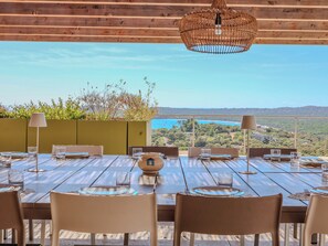 A dining table set for four with a view of the sea and hills in the background. - Villa Ghjiseppina Di Pinarello (Porto-Vecchio)