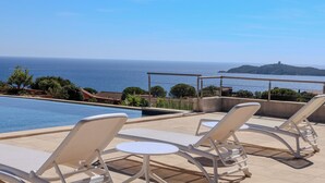 A poolside area with lounge chairs and a view of the sea. - Villa Ghjiseppina Di Pinarello (Porto-Vecchio)