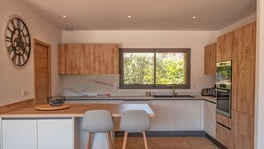 A modern kitchen with wooden cabinets, a marble backsplash, a built-in oven, and a window providing natural light. - Villa Felicita di Lecci (Lecci)