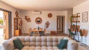 A modern living room with a beige sofa, a dining table with chairs, and decorative wall art. - Villa Felicita di Lecci (Lecci)
