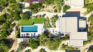 Vista aerea di una casa moderna con piscina, immersa nel verde e circondata da un giardino curato.