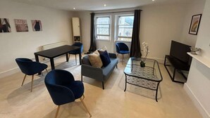 Un salon moderne comprenant un canapé, des fauteuils, une table à manger et un téléviseur.