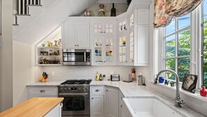 A kitchen with white cabinets, a microwave, stove, and a sink.