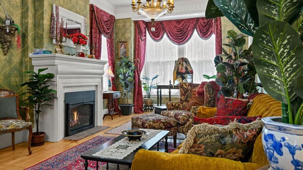 A traditional living room with a fireplace, ornate furniture, and lush green plants.
