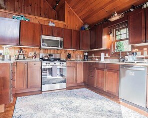 Une cuisine avec des meubles en bois, un four à micro-ondes, une cuisinière et un lave-vaisselle.