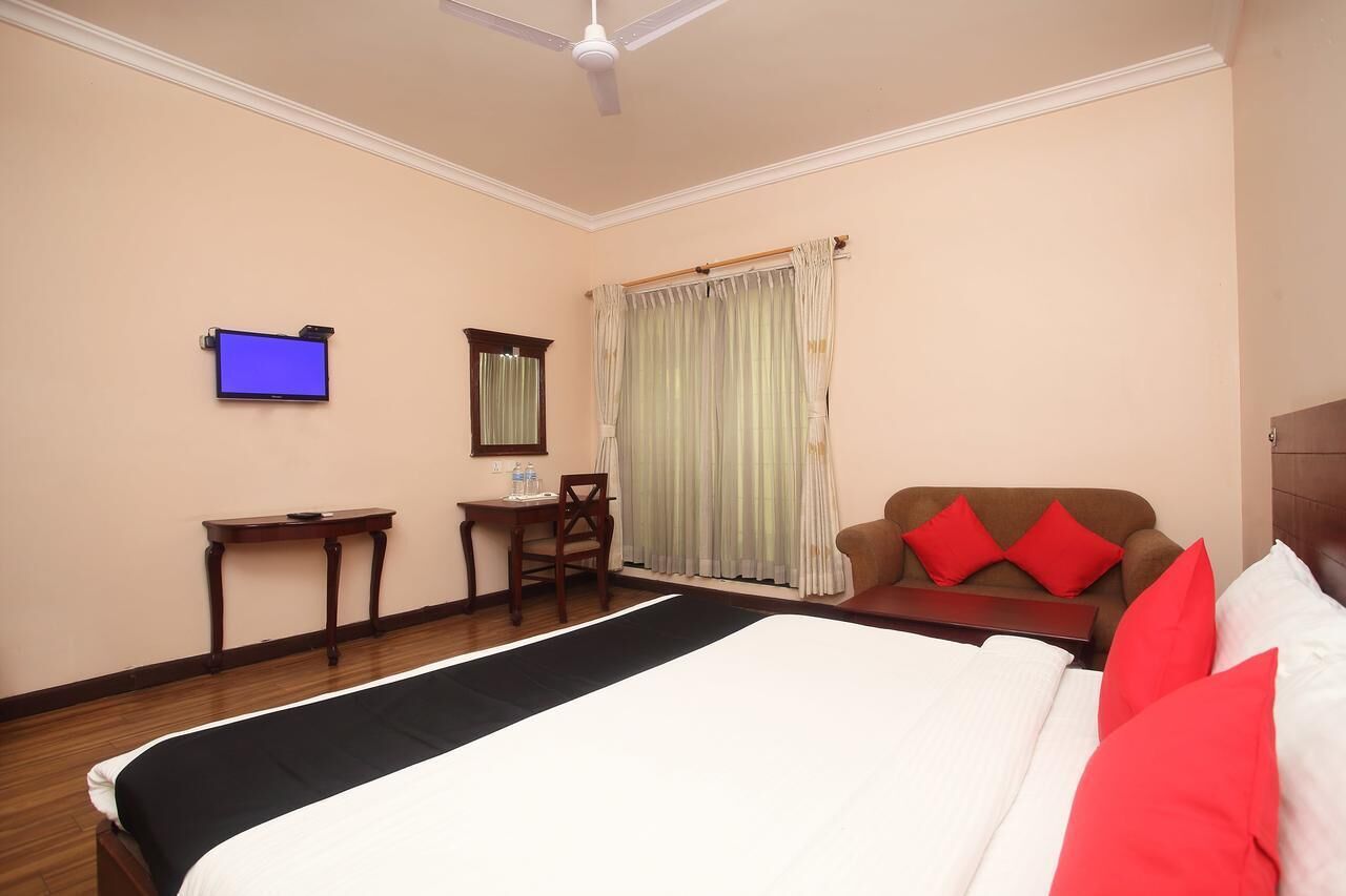A hotel room with a bed, a desk, a chair, a television, and a window with curtains.
