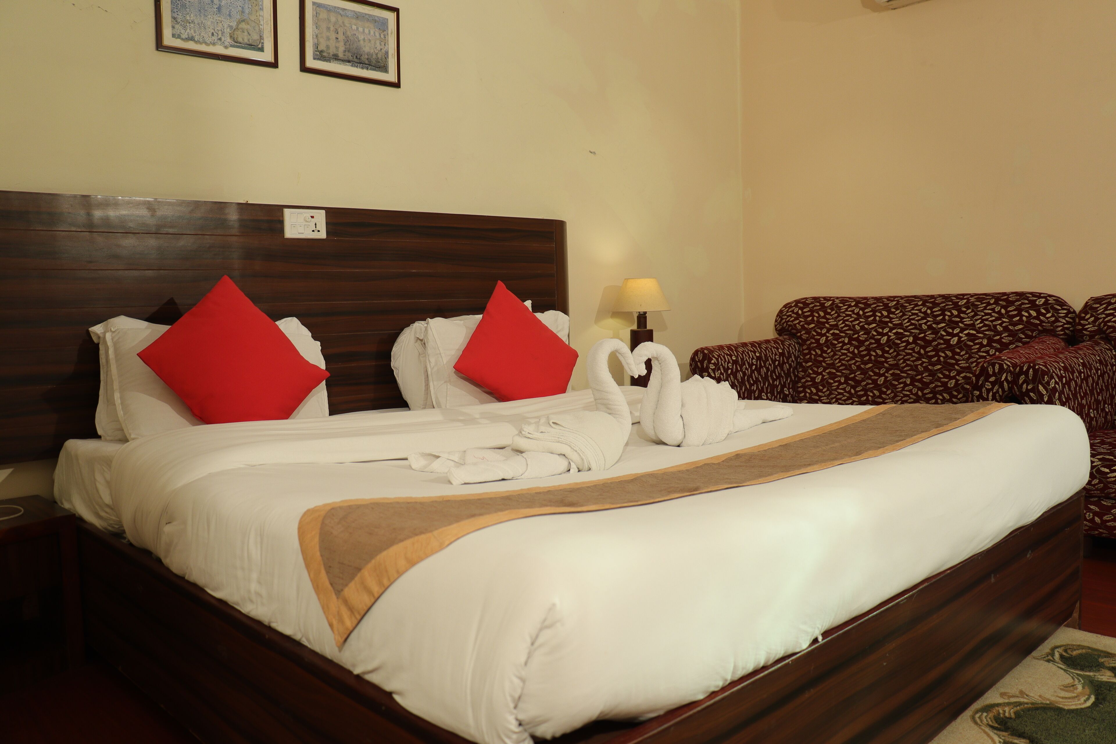 Uma cama bem arrumada com almofadas vermelhas, cabeceira de madeira e luminária de cabeceira.