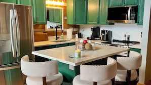 A kitchen with green cabinets, a stainless steel refrigerator, a microwave, and a coffee maker. There are three white chairs with a cushioned seat and backrest. - 3-bedroom cabin in serene Banner Elk on 8 Acres with Mountain View’s (Banner Elk)