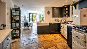Une cuisine avec des meubles de couleur sombre, une cuisinière et un coin repas comprenant une table et des chaises.