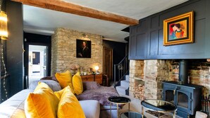 Un salon chaleureux avec un mur en pierre, une cheminée et un escalier menant à un autre niveau.