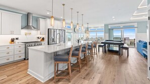 Una cocina moderna con armarios blancos, electrodomésticos de acero inoxidable y una isla central con taburetes de bar.