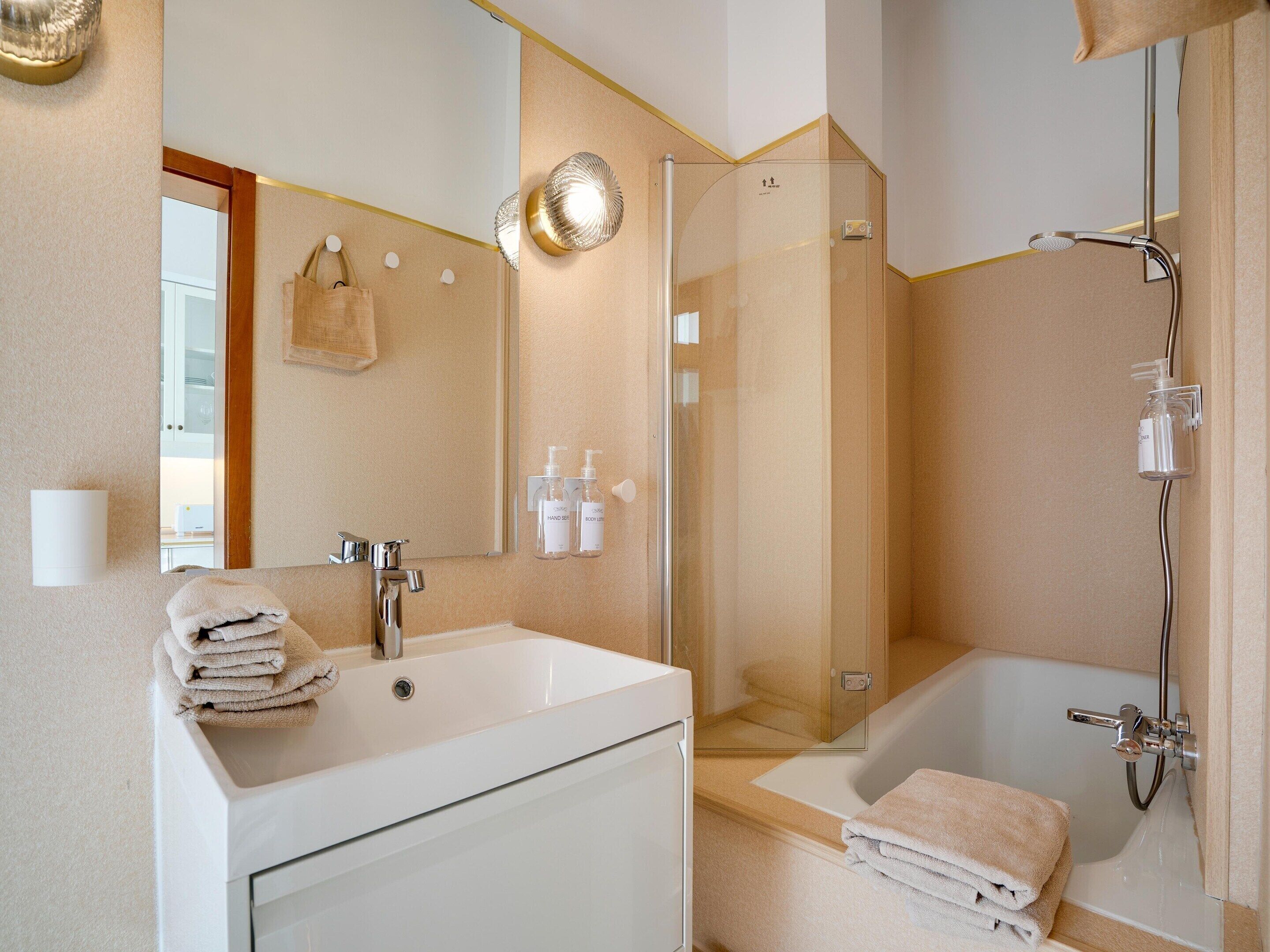 Une salle de bain moderne avec un lavabo blanc, une douche à parois de verre et une baignoire.