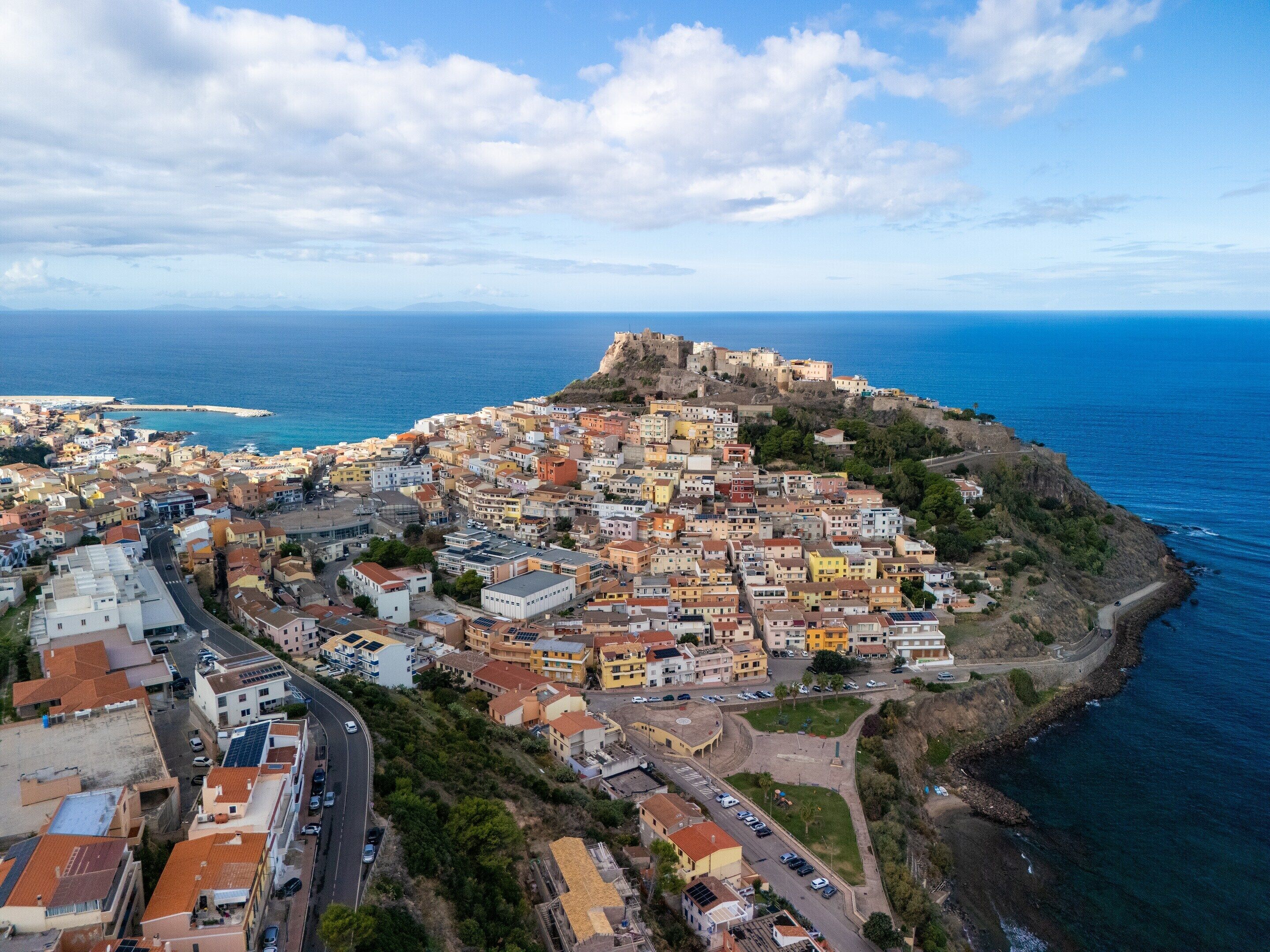 A coastal town with historic buildings, a prominent fort, and a clear view of the sea.