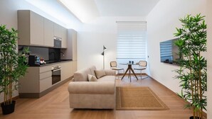 A modern apartment with a kitchen, a sofa, a dining table, and two potted plants. - Luca Stay Duomo Visconti Suites (Milan)