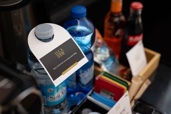 Un mini-bar contenant une bouteille d’eau, une bouteille de Coca-Cola et une petite carte avec du texte.