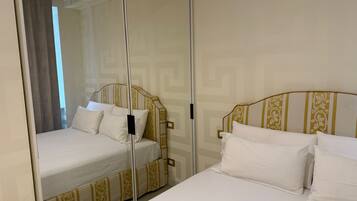Ein Hotelzimmer mit zwei Betten, jeweils mit einem gemusterten Kopfteil und weißer Bettwäsche.