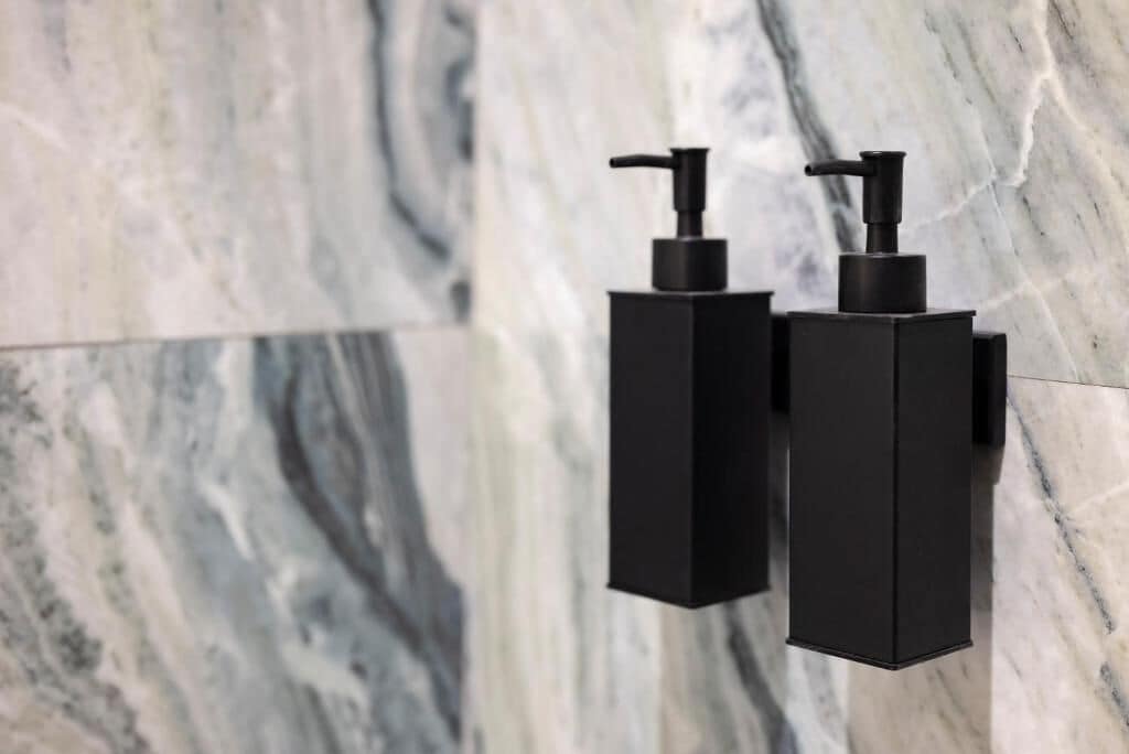 Twee zwarte zeepdispensers, bevestigd aan een marmeren muur.