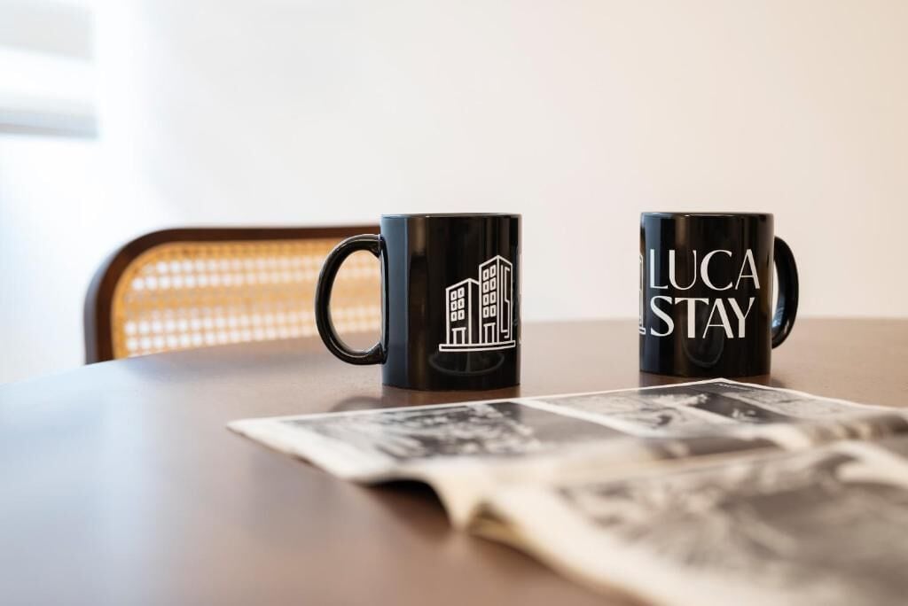 Two black mugs with white text on a table.