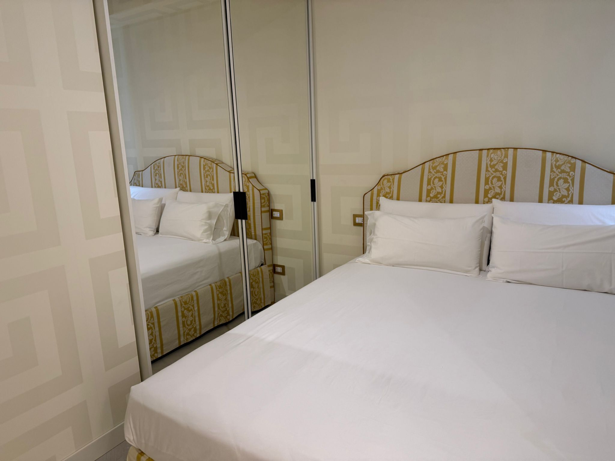 Une chambre d’hôtel avec deux lits, dont l’un est doté d’une tête de lit à motifs et l’autre est de couleur unie.