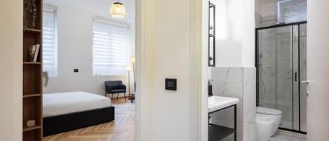 Un dormitorio moderno con una cama, una estantería de madera y una lámpara colgante.