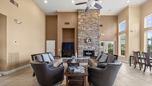 Amplia sala de estar con chimenea de piedra, sofás de cuero, una mesa de centro y un comedor con sillas.