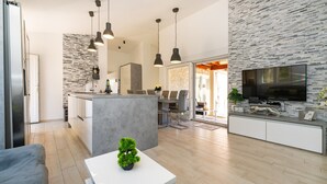Un espace de vie moderne comprenant une cuisine, un coin repas et un téléviseur.