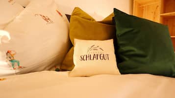 Una cama con varias almohadas, algunas con texto e ilustraciones.