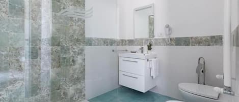 A bathroom with a glass shower enclosure, a white sink, and a toilet.