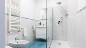 A modern bathroom with a glass shower enclosure, a sink, and a toilet.