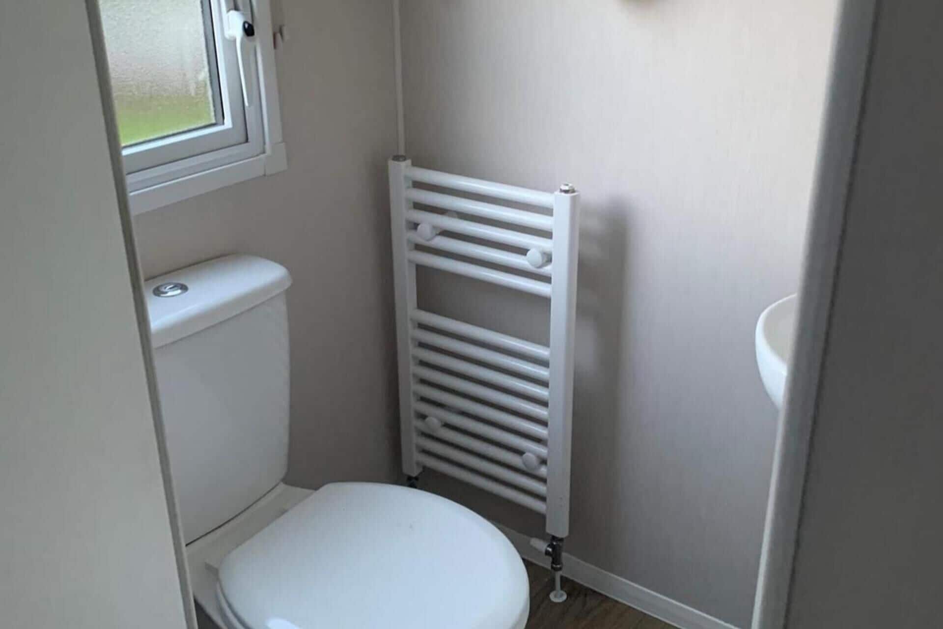 A small, compact bathroom with a toilet, a radiator, and a sink.