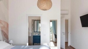 A bedroom with a bed, a dresser, a mirror, and a television on the wall.