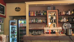 A bar area with shelves of liquor bottles, a refrigerator with drinks, and a coffee machine.