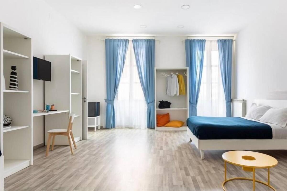 A modern bedroom with a bed, a desk, and a wardrobe.