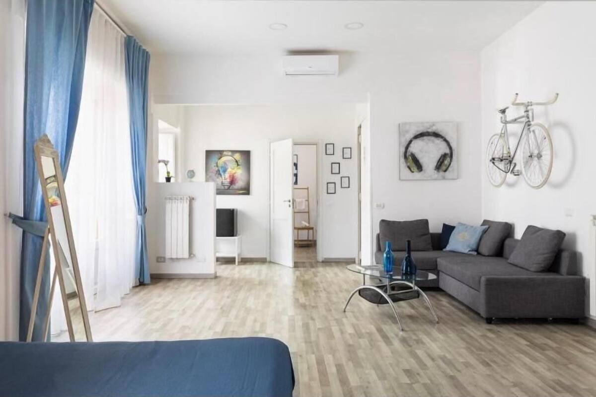A modern living room with a grey sofa, a coffee table, and a bicycle mounted on the wall.