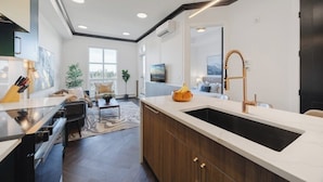A modern kitchen with a large island, built-in oven, and a farmhouse sink.