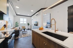 A modern kitchen with a large island, built-in oven, and a farmhouse sink.