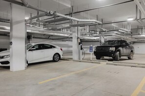 A parking garage with multiple levels, concrete pillars, and overhead pipes.