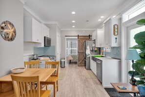 Una cocina moderna con armarios blancos, una mesa de comedor de madera y un amplio ventanal.