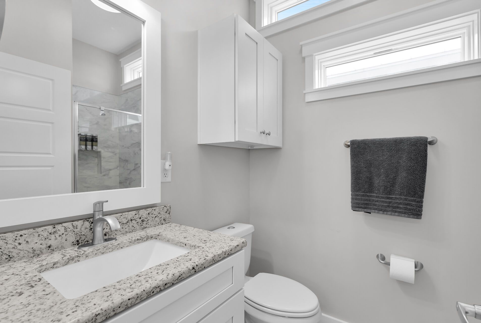 A bathroom with a white sink, a mirror, a toilet, and a towel hanging on the wall.
